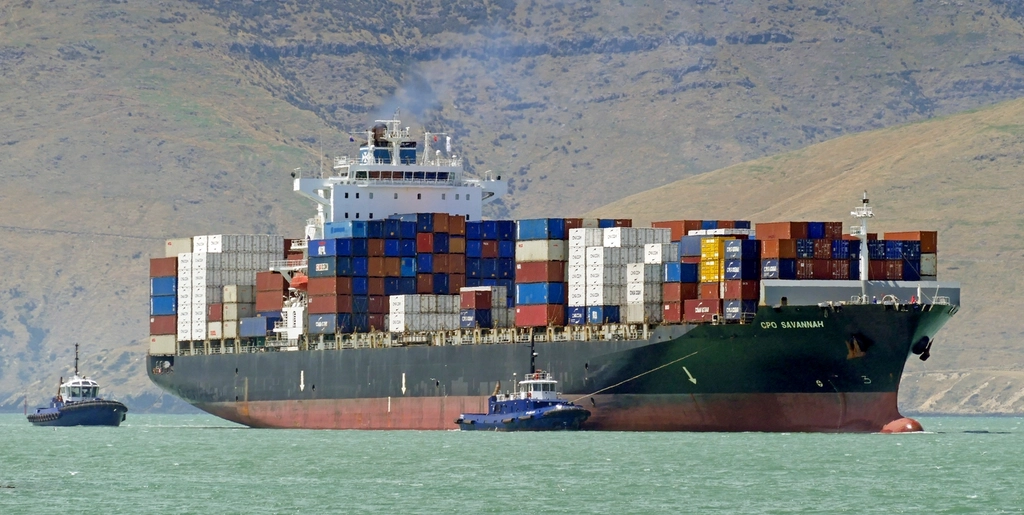 Container ship under way with tugs alongside